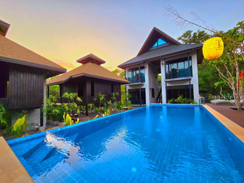 a house with a blue swimming pool in front of a house at Baan Koh Kwang Pool Villa Krabi in Krabi