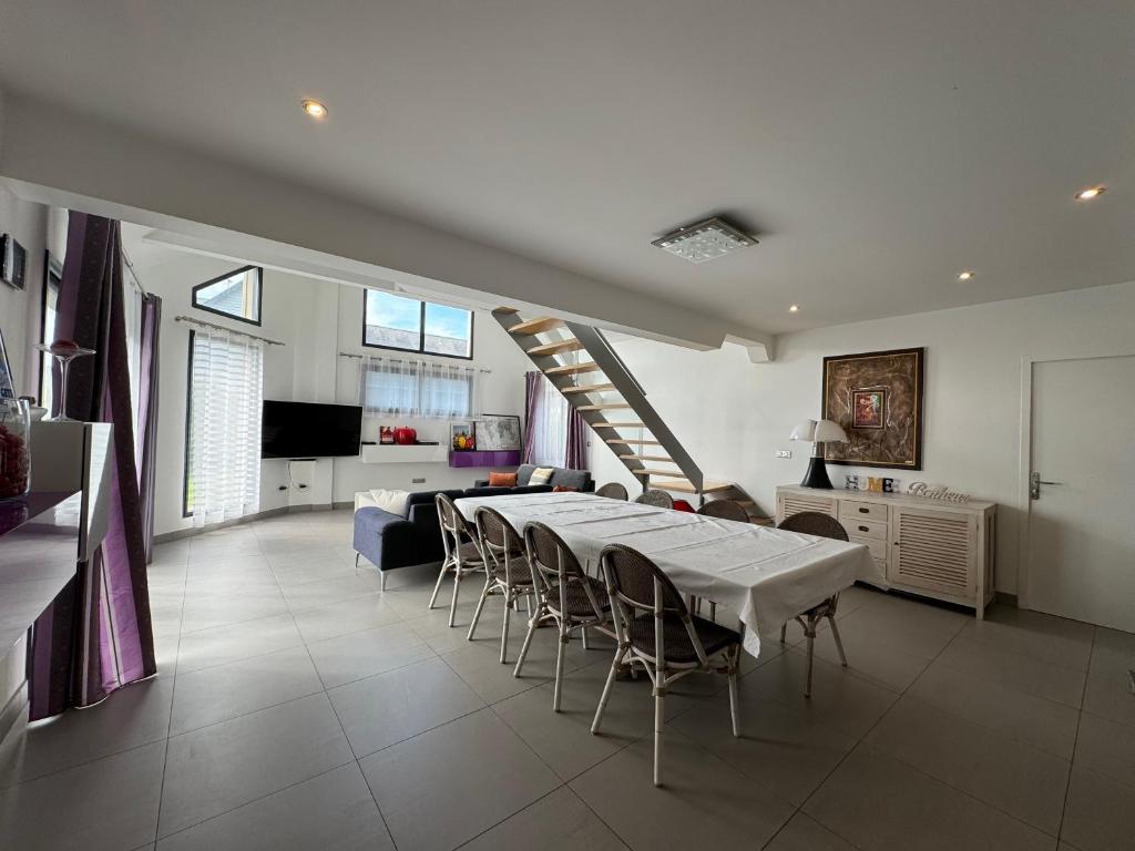 uma sala de estar com uma mesa e cadeiras e uma escadaria em Villa Benouville em Bénouville