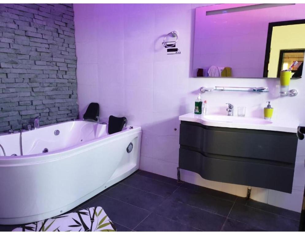 a white bathroom with a tub and a sink at Belle Appartement avec Jaccuzzi à Diamniadio in Dakar