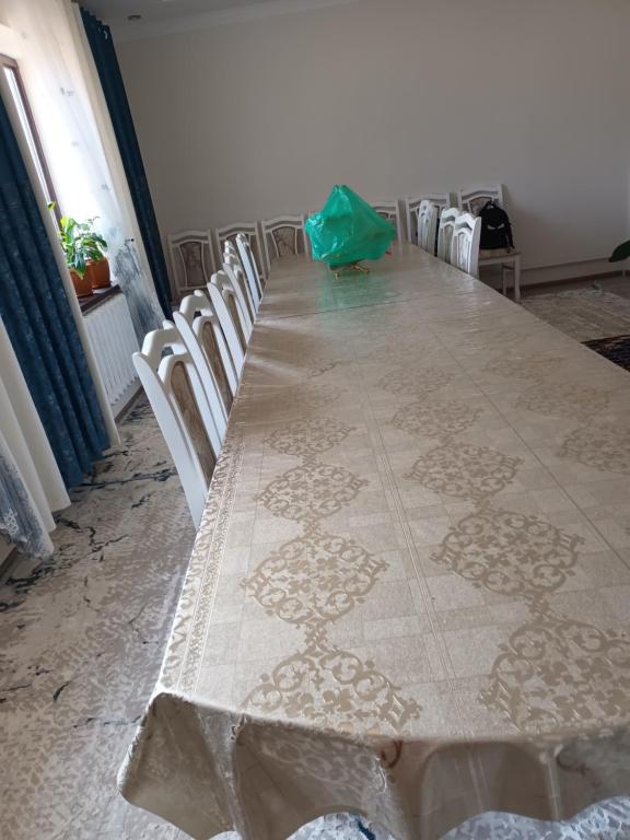 einen langen Tisch mit Stühlen und eine grüne Tasche darauf in der Unterkunft Guest Houst Akkyya in Akkyya