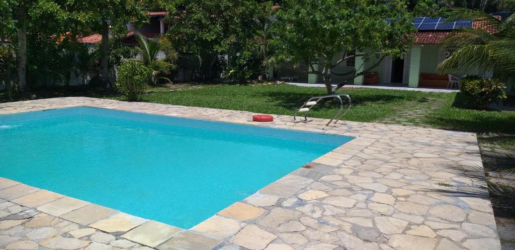 a swimming pool with a chair in a yard at A Bela Casa da Ilha, na Ilha de Vera Cruz, Coroa, 300m da praia! in Salvador