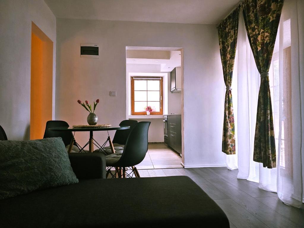 ein Wohnzimmer mit einem Tisch, Stühlen und einem Fenster in der Unterkunft Apartment Port of happiness in Krnica