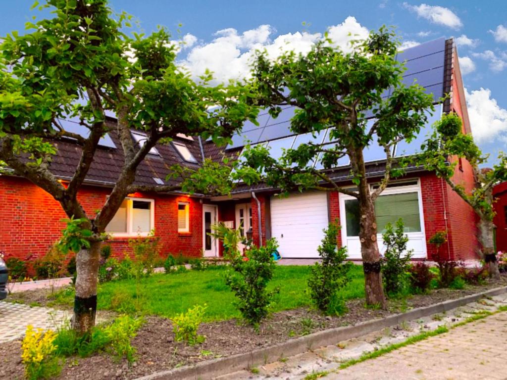 ein rotes Haus mit Bäumen davor in der Unterkunft Ferienwohnung Südpol, Pellworm in Pellworm
