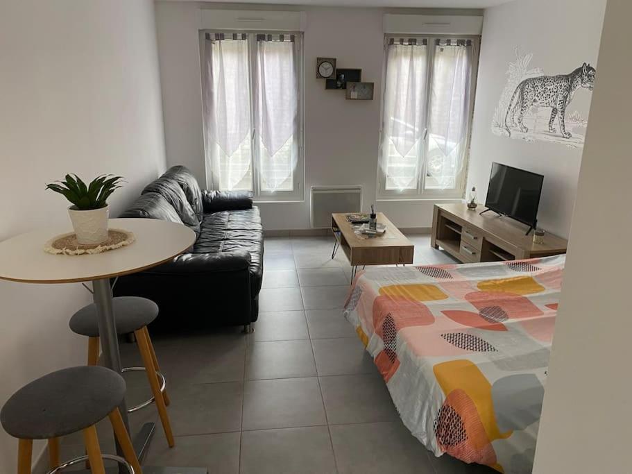 a living room with a bed and a table and a couch at Studio en rez-de-chaussée avec cour dans le centre de Vendome in Vendôme