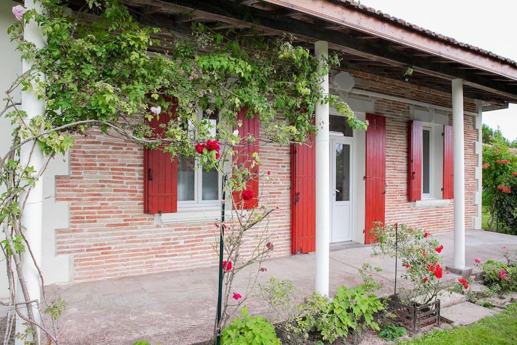 une maison en briques avec des volets rouges et un arbre dans l'établissement Maison familiale proche du lac, à Biscarrosse