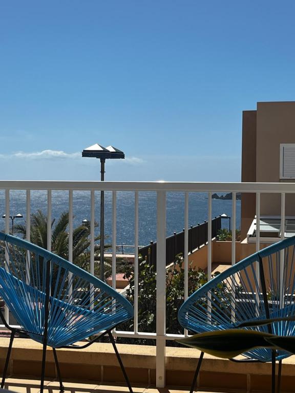 twee blauwe stoelen op een balkon met uitzicht op de oceaan bij El Poris in Poris de Abona