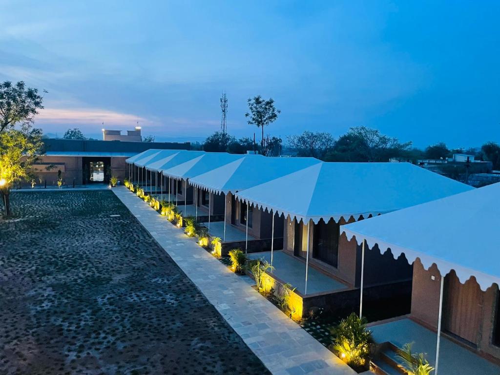 a row of buildings with blue umbrellas at night at Nightingales Resort in Nāthdwāra