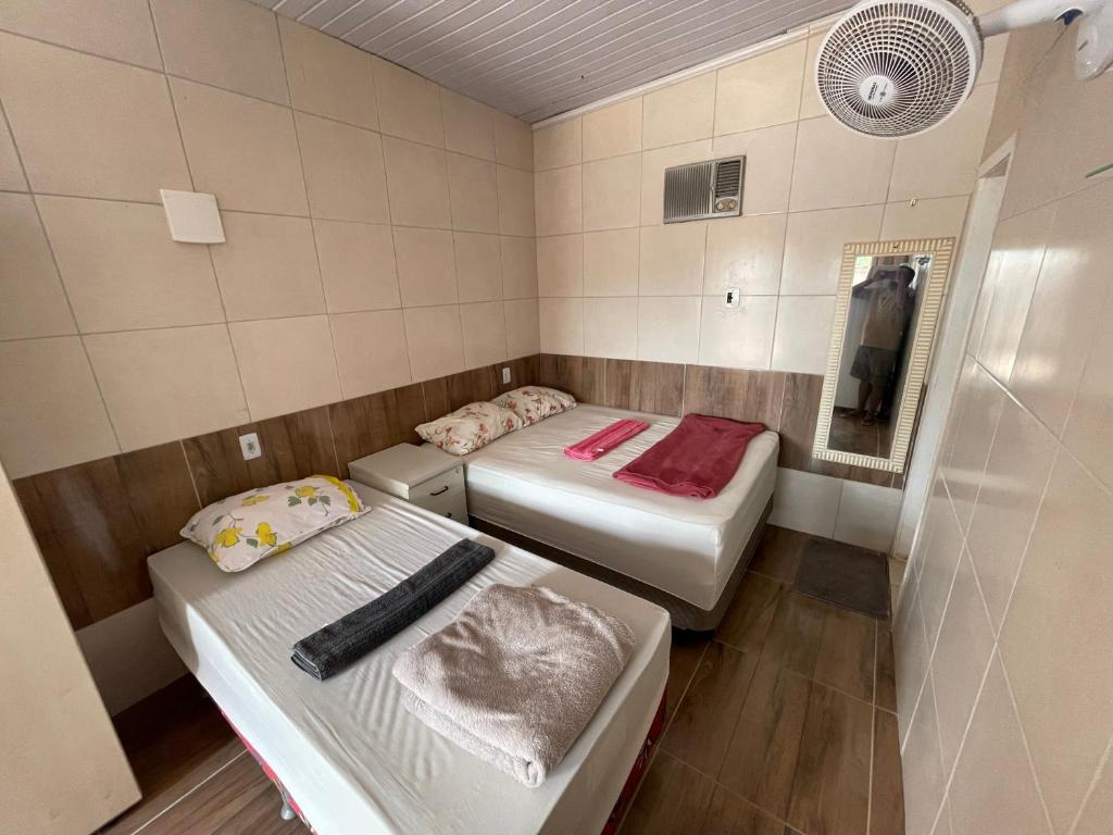 a small room with two beds and a fan at Hospedaria cmc unidade 05 com estacionamento in Brasilia