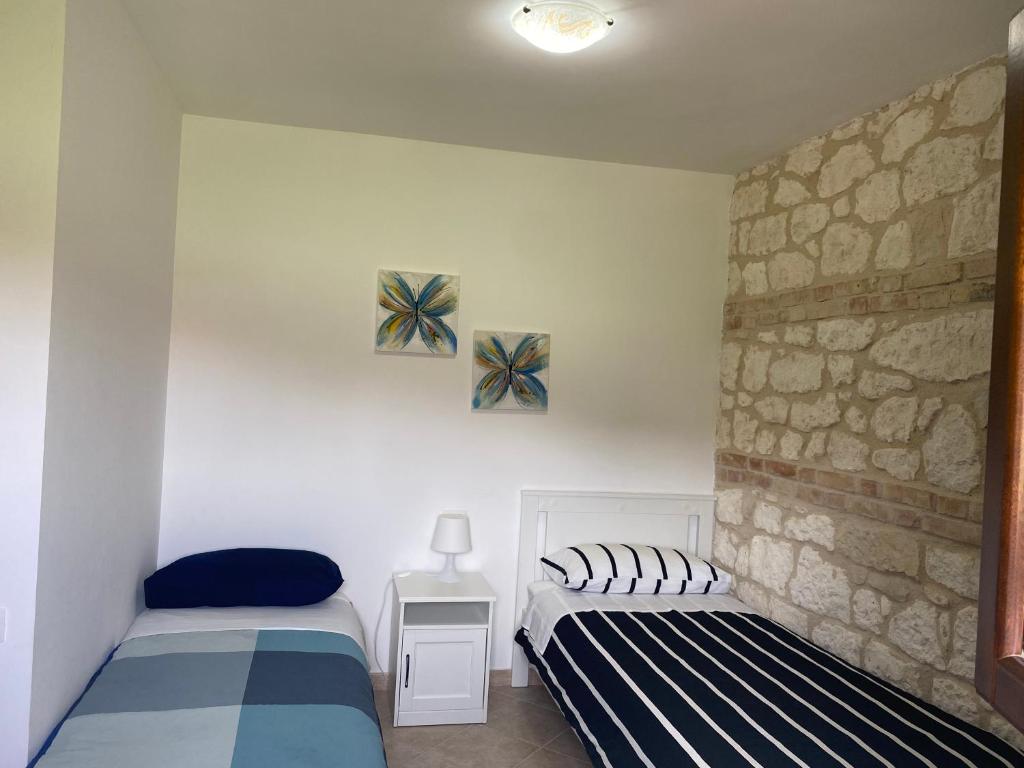 a bedroom with two beds and a stone wall at Pezzelelle in Roccamorice