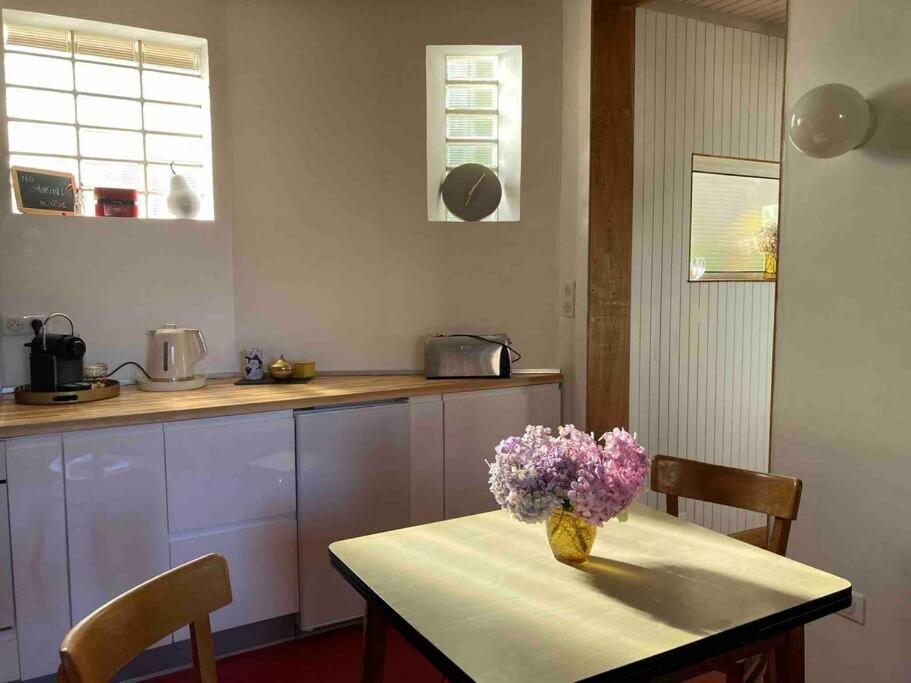 a kitchen with a table with a vase of flowers on it at Villanelle maison en centre hyper calme et au vert in Limoges