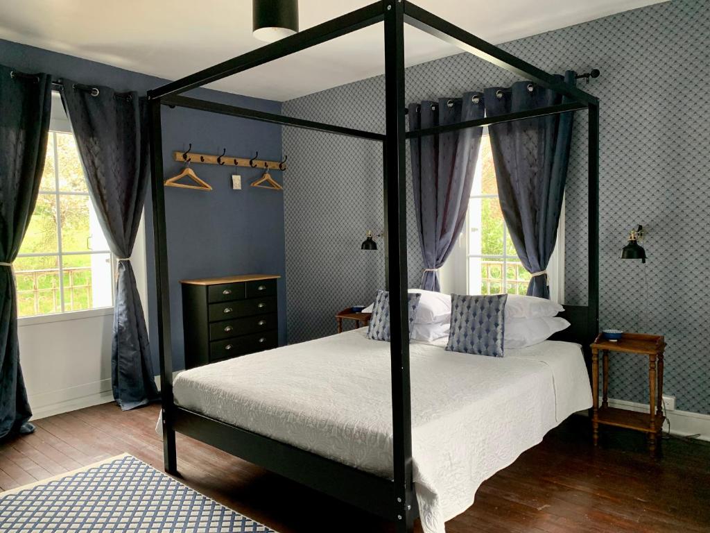 a bedroom with a black canopy bed with white sheets at Brigitte et Moi in Chancelade