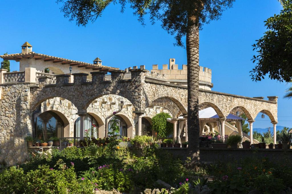 un edificio de piedra con un árbol delante de él en Castell Bohio, en Urbanización Ses Palmeres