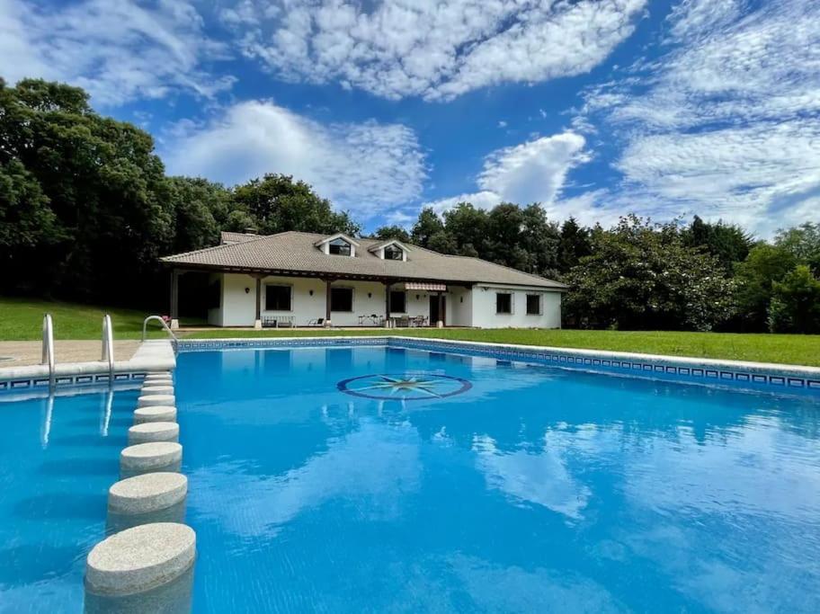 a large swimming pool with a house in the background at La Hondonada. in Somo