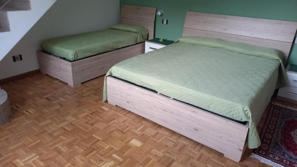 two beds in a room with wooden floors at La casetta di campagna in Mazzo di Valtellina