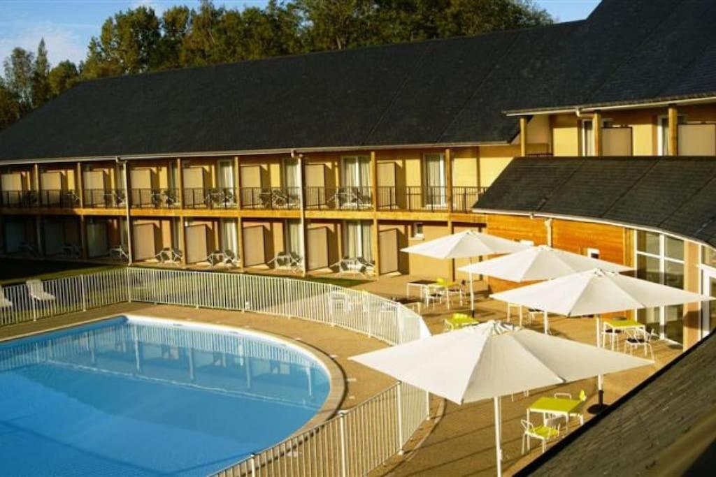 un hôtel avec une piscine et des parasols dans l'établissement Studio cosy ac piscine proche de Honfleur - 10 min, à Équemauville