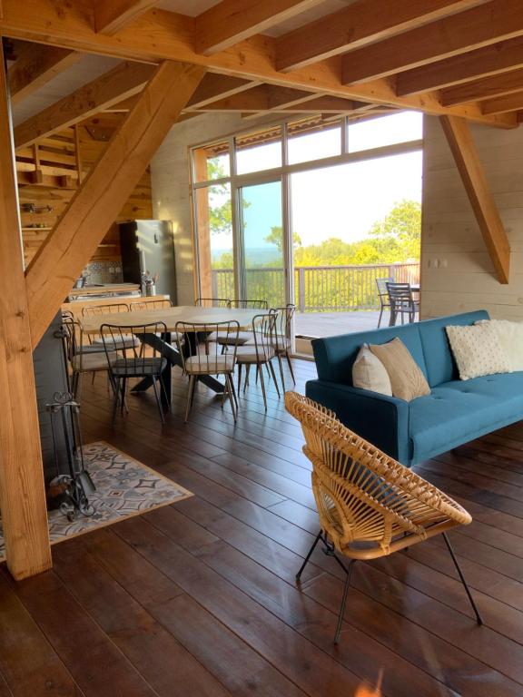 un salon avec un canapé bleu, une table et des chaises dans l'établissement Maison bois, proche Sarlat, à Domme