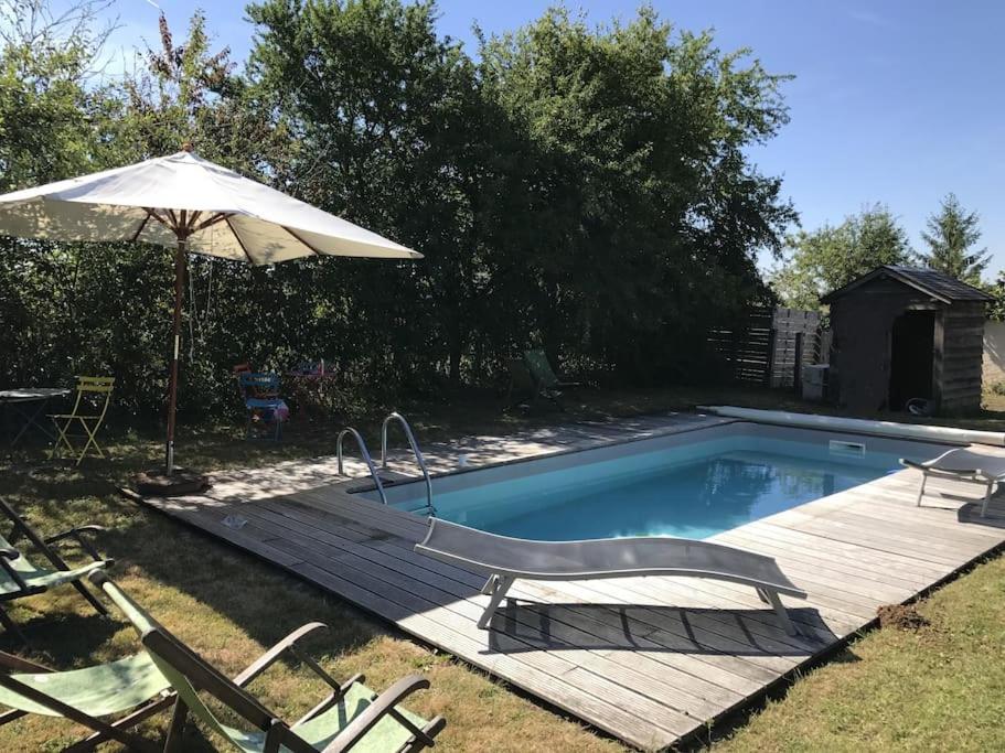a swimming pool with a wooden deck and an umbrella at Maison de charme avec piscine in Vignoux-sous-les-Aix