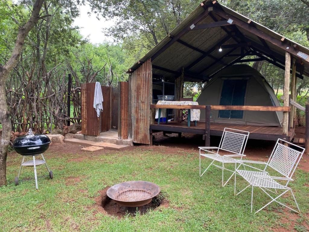 a gazebo with chairs and a grill in a yard at Soetvlei Tented Farm Camp in Magaliesburg