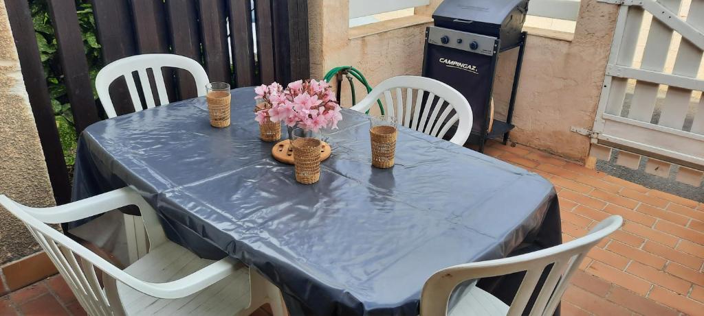 - une table bleue avec des chaises blanches et des fleurs dans l&#39;établissement Maison de la plage, à Valras-Plage