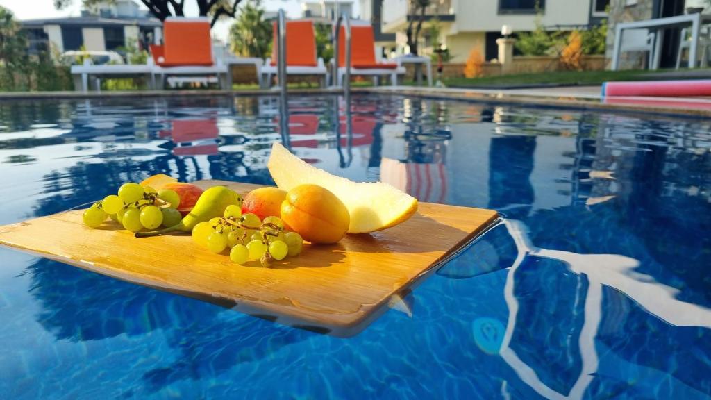 a cutting board with fruit on top of a swimming pool at Villa Begonvil in Kuşadası