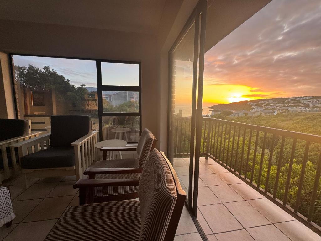 a balcony with chairs and a view of a sunset at Chandos Apartment Vleesbaai in Vleesbaai
