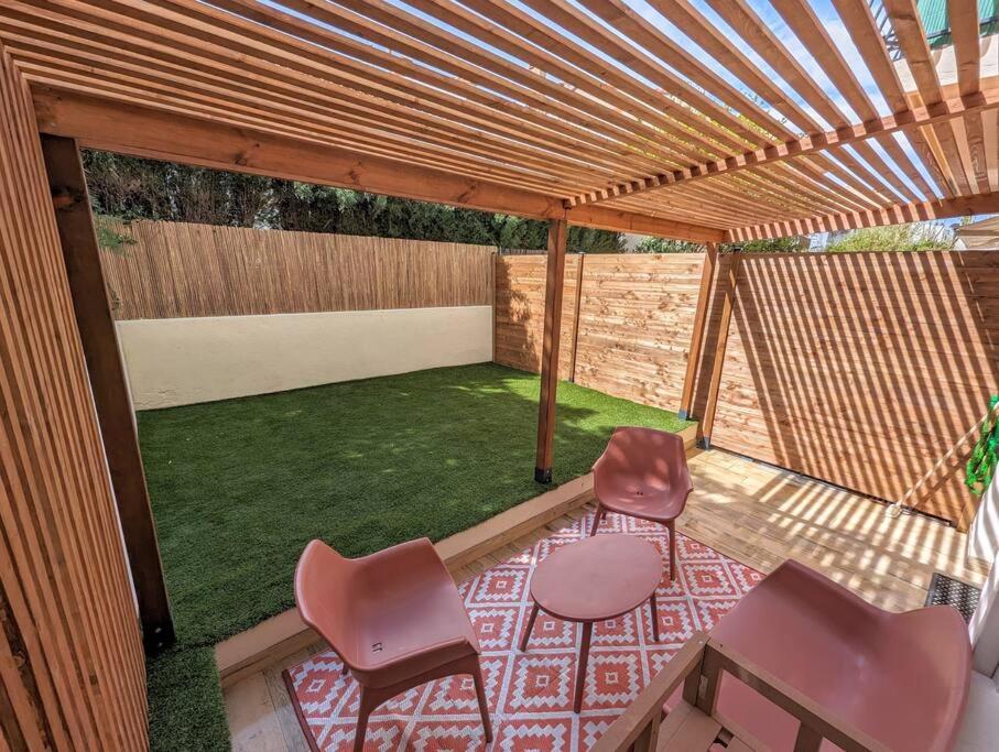 uma pérgola com duas cadeiras e uma mesa e alguma relva em Le numéro 1 em Perpignan