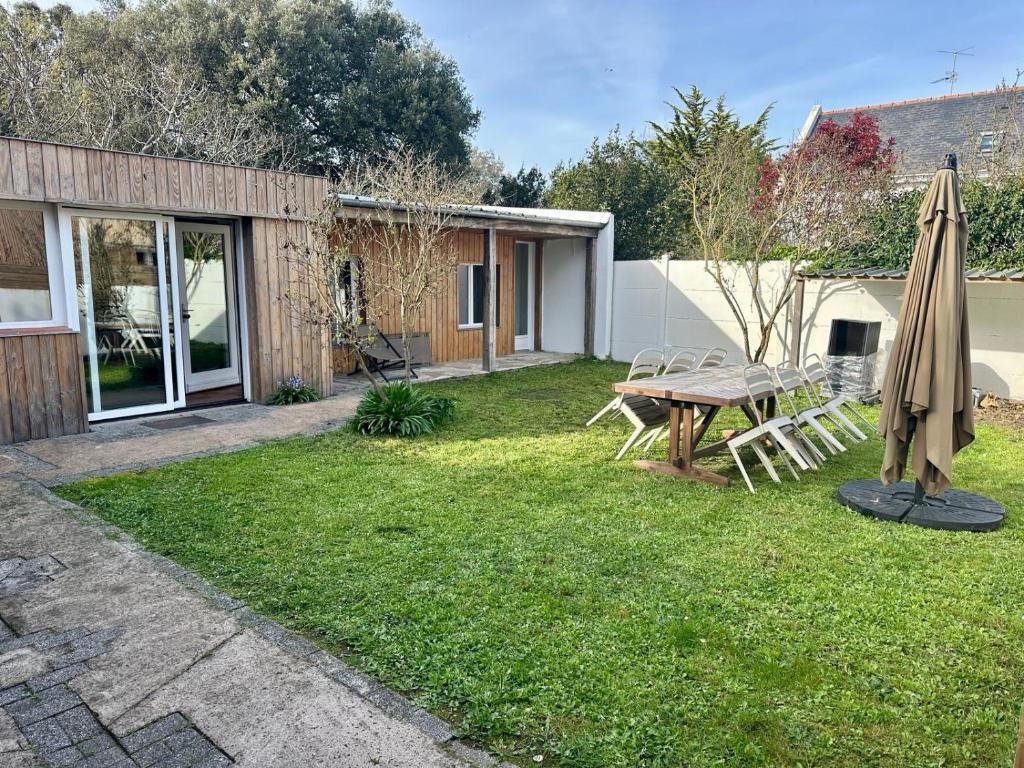 - une terrasse avec une table et un parasol dans la cour dans l'établissement Terracotta - Belle maison, 2 chambres, jardin - Plages et commerces à pied, au Croisic