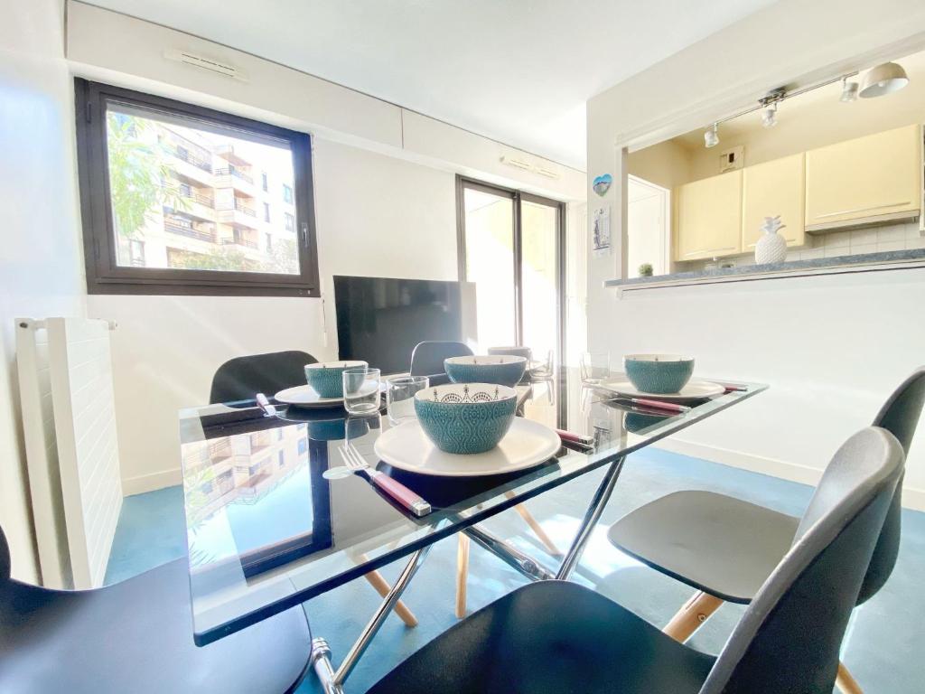 ein Esszimmer mit einem Glastisch und Stühlen in der Unterkunft Superbe appartement terrasse in Levallois-Perret
