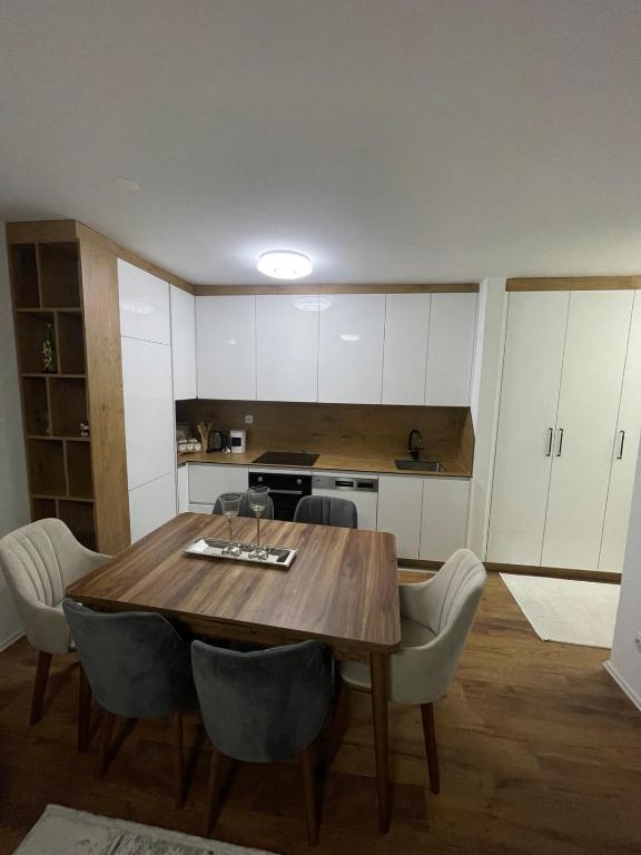 Luxury Apartment في Gnjilane: مطبخ مع طاولة خشبية ودواليب بيضاء
