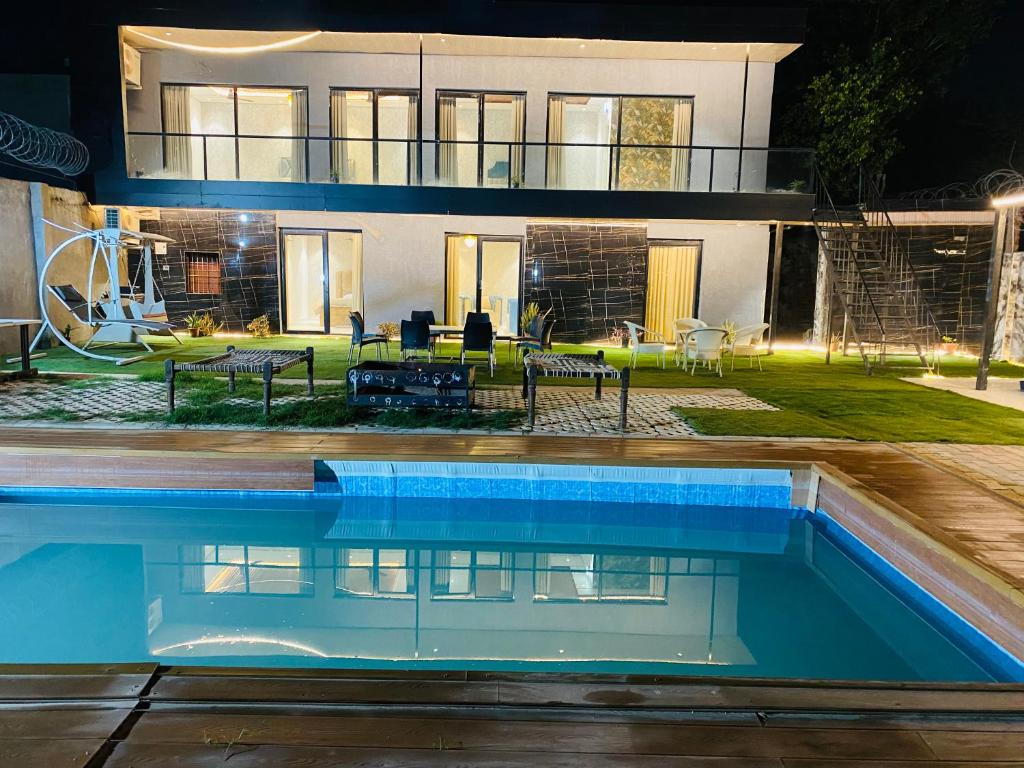 a house with a swimming pool at night at Farmhouse with pol near golf course road,Gurgaon in Gurgaon