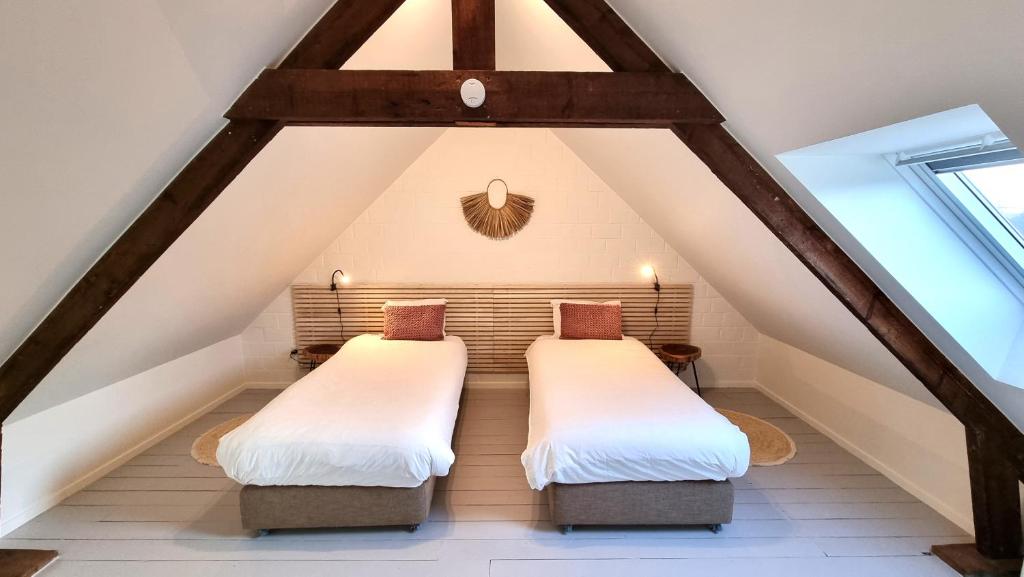 two beds in a attic bedroom with wooden beams at Casa Rosalie in Lokeren