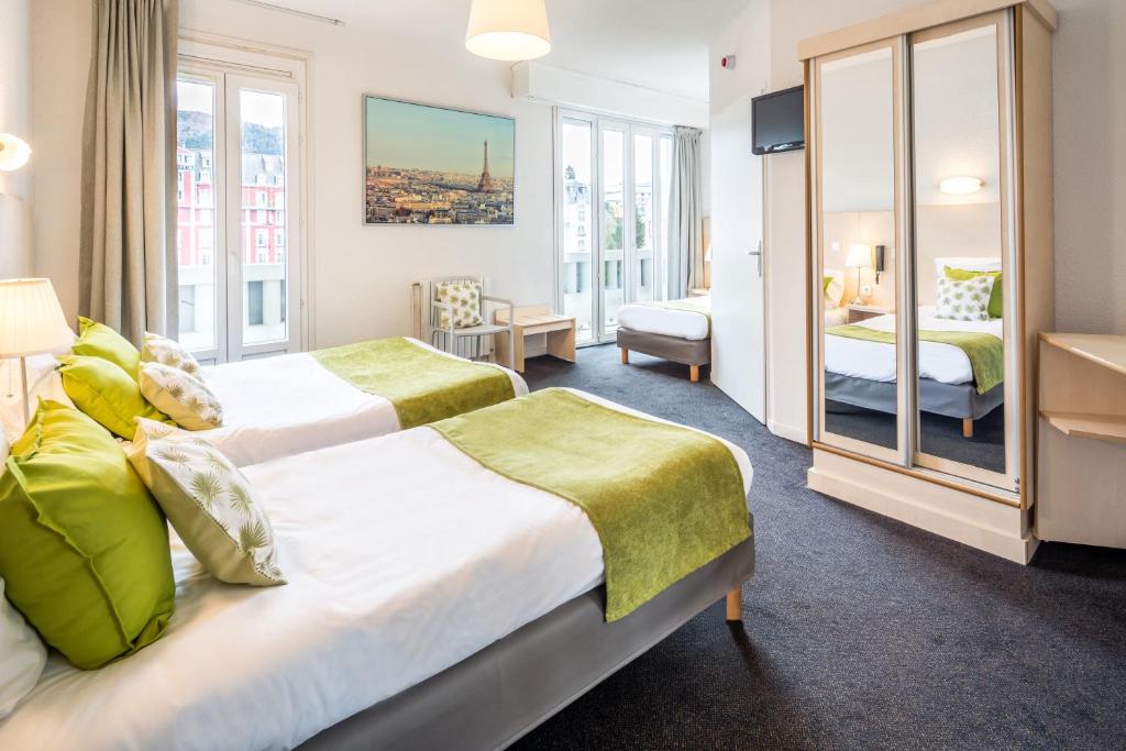 a hotel room with two beds and a mirror at Hôtel Notre Dame de France in Lourdes