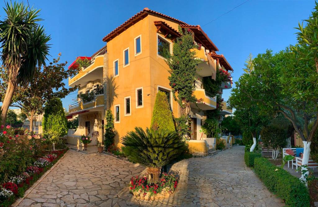 een geel gebouw met bloemen ervoor bij Flower Garden Villa in Ksamil