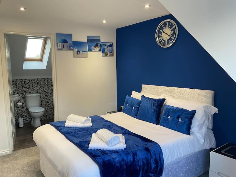 ein blaues Schlafzimmer mit einem großen Bett mit einer Uhr an der Wand in der Unterkunft The WestField in Liversedge