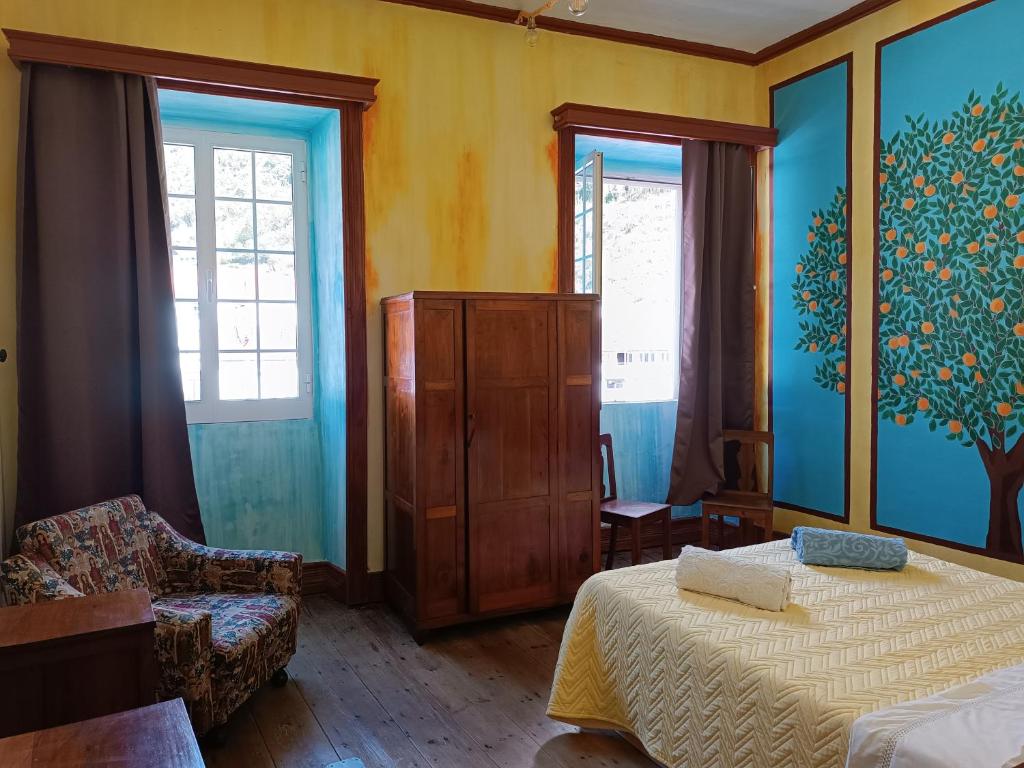 a bedroom with a bed and a dresser and two windows at Avó da Rosa 2 in Faial da Terra
