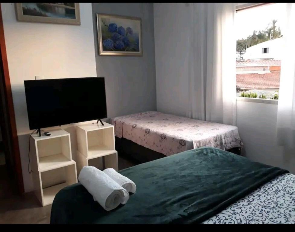 um pequeno quarto com 2 camas e uma televisão em Triboulet hospedaria em Campinas