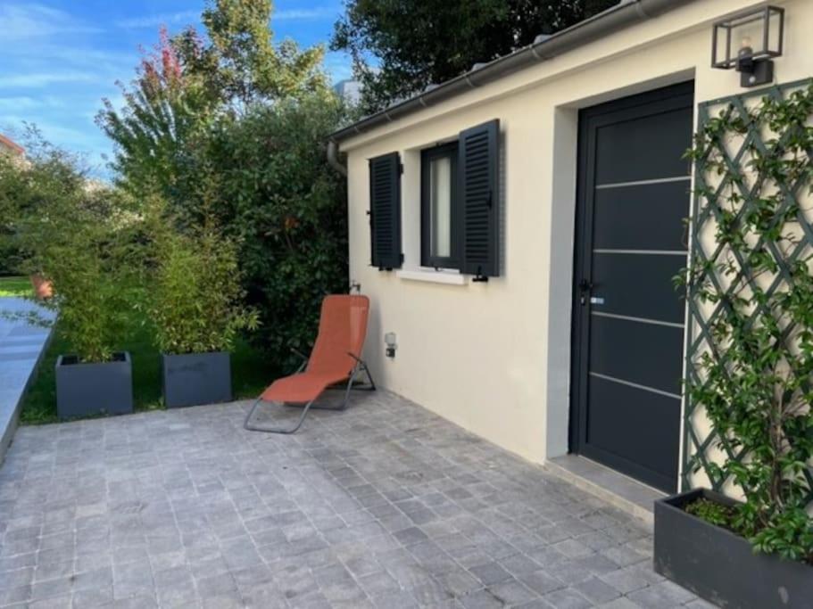 una sedia arancione seduta di fronte a un garage di Studio neuf s/jardin, très calme a Colombes