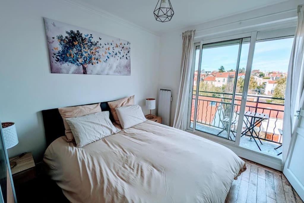 um quarto com uma cama e uma grande janela em 2 pièces Cosy avec vue Panoramique et Balcon ! em Rosny-sous-Bois