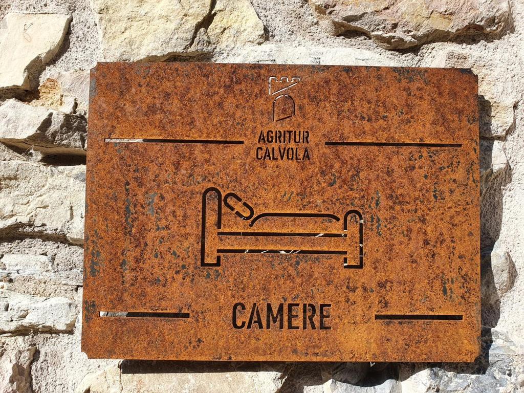 ein Schild an der Seite einer Steinmauer in der Unterkunft Agritur Calvola in Tenno