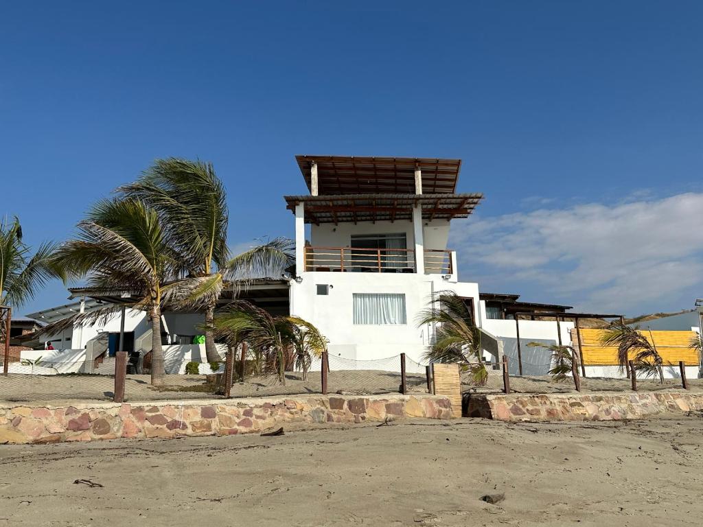 a white building with palm trees in front of it at Las Fragatas Casa Hotel Eventos para 40 personas in Canoas de Punta Sal
