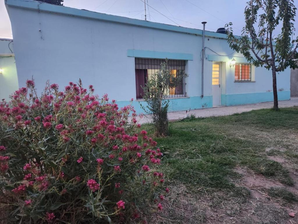 a white building with pink flowers in front of it at Casa Verde in Centenario