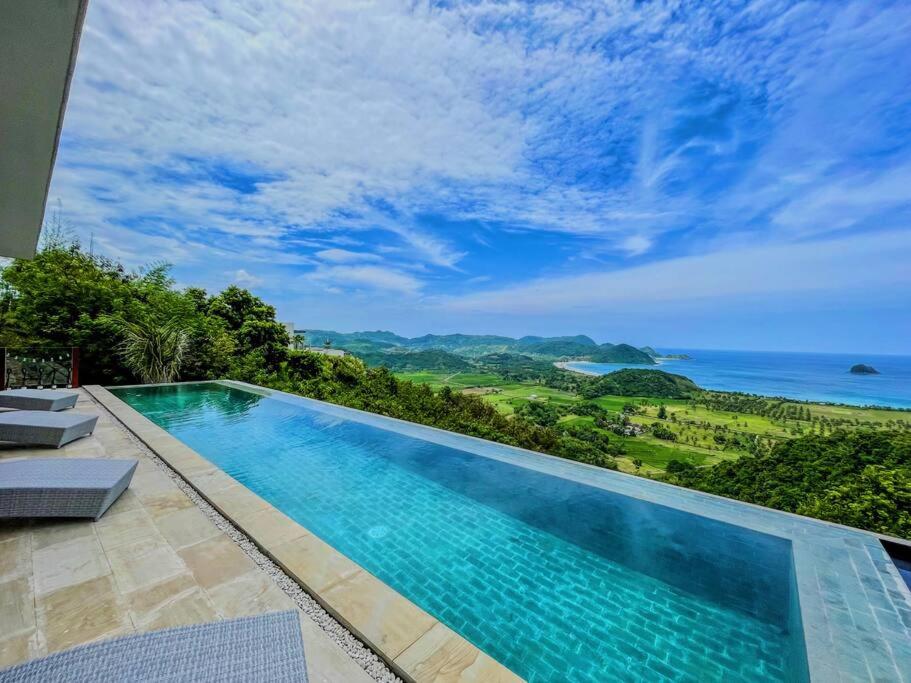 a swimming pool with a view of the ocean at Ocean Wave Lombok - 4 BR infinity pool villa in Selong Belanak
