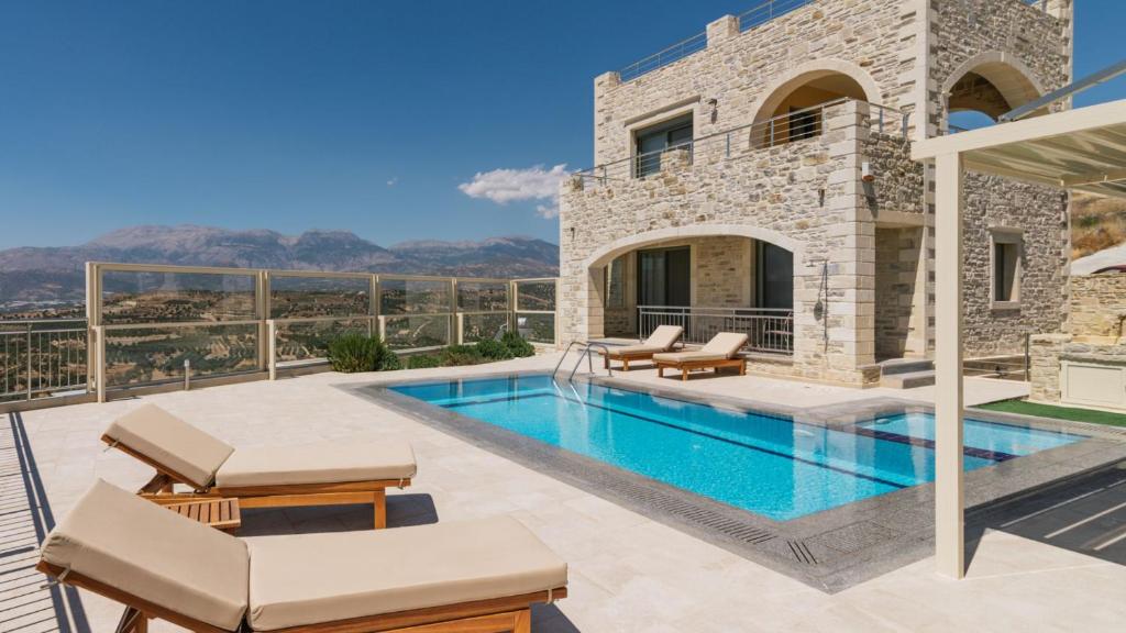 a villa with a swimming pool and a patio at Villa Ovgoro - Luxury 3-Level Villa with Heated Pool, Jacuzzi and Panoramic Views in Kamilari