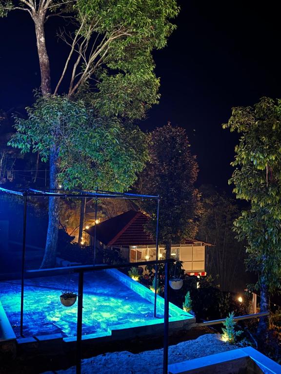 una piscina iluminada por la noche en Coorg Heritage Hill View Resort en Madikeri