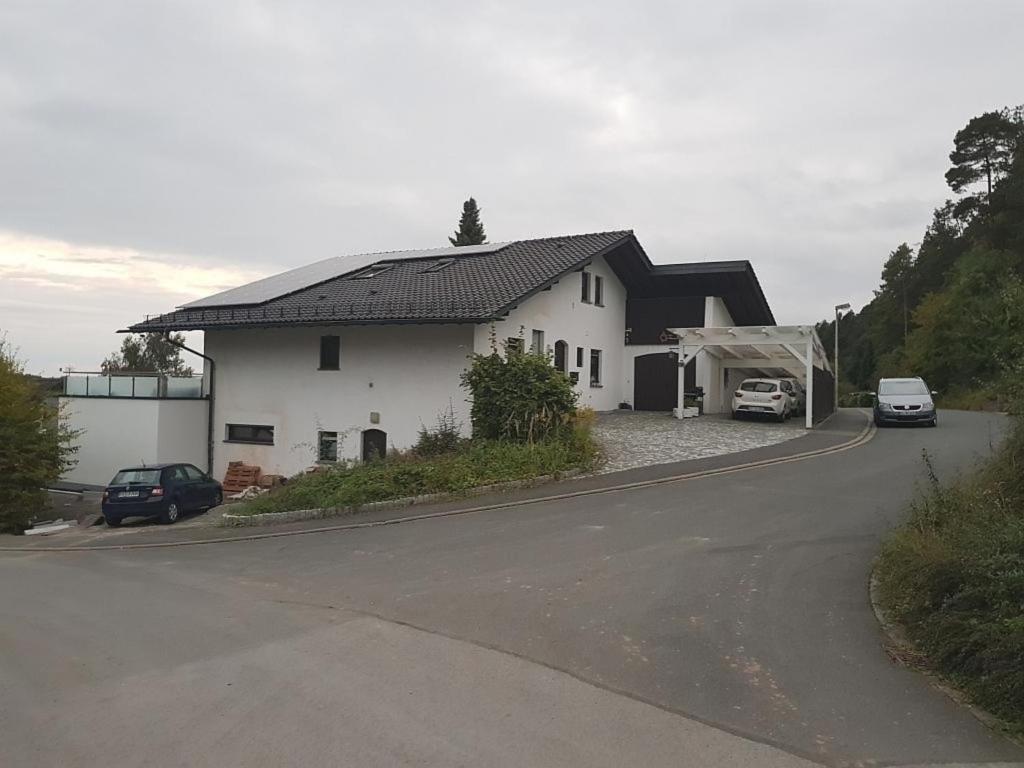 una casa blanca con techo negro en una carretera en Wunderschöne klimatisierte Wohnung in Weidach 