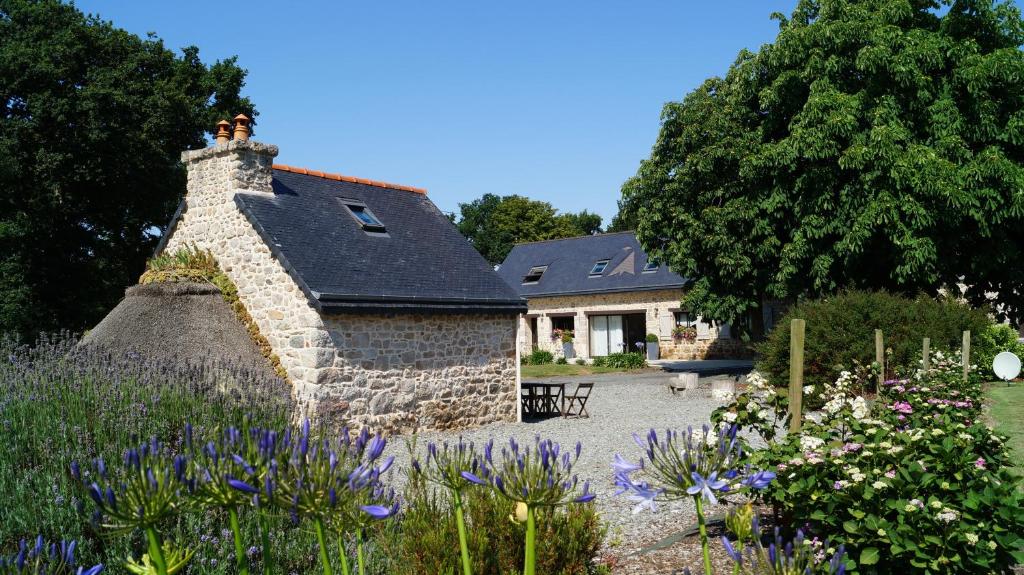 a stone house with a garden in front of it at À L'orée Du Bois in Pommerit-le-Vicomte