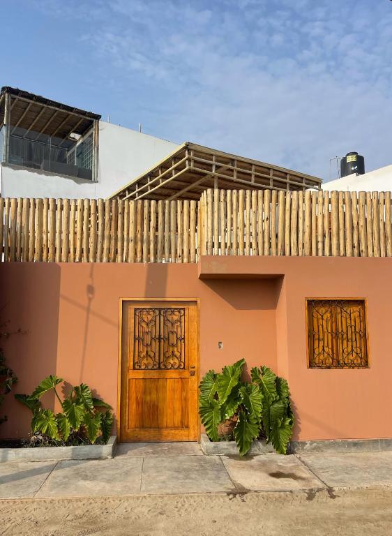 una casa con una porta in legno e una recinzione di El Templo Surf House a Punta Hermosa