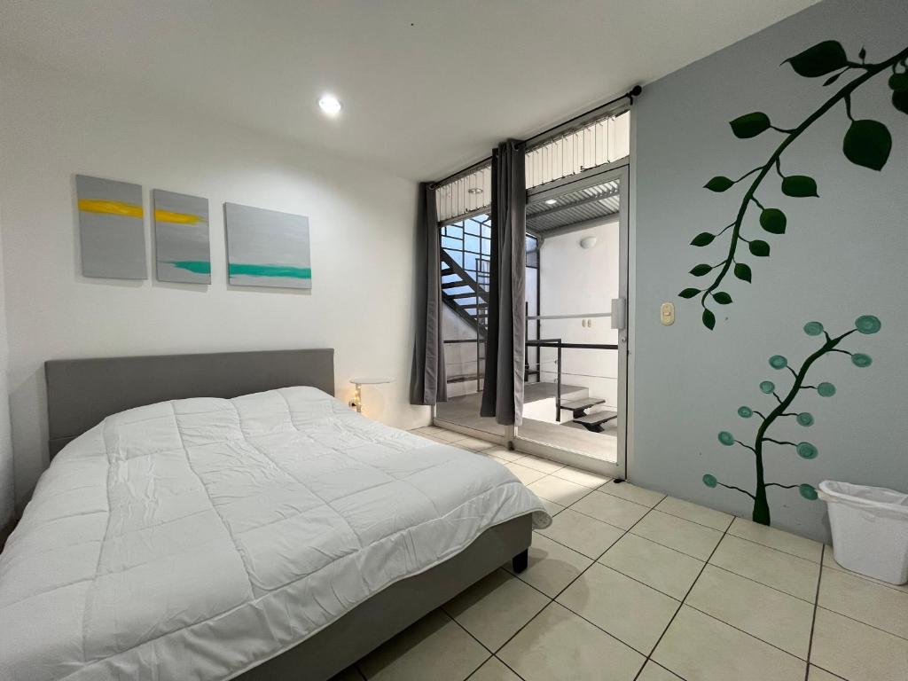 a bedroom with a bed and a large window at SJO Oasis Hostel in San José