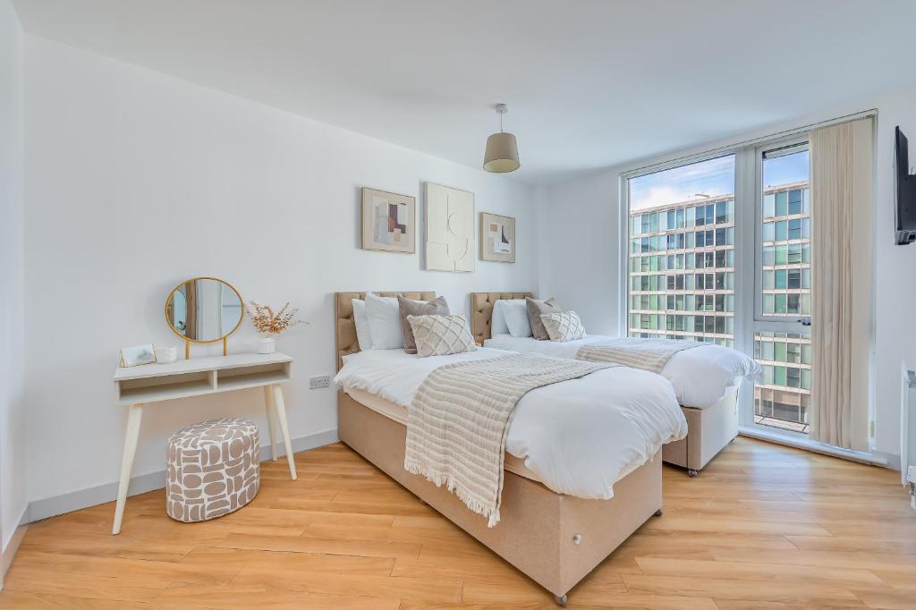 Duas camas num quarto branco com uma janela em Stunning City Centre Apartment with Balcony, Free Parking, Fast Wifi and SmartTVs by Yoko Property em Milton Keynes