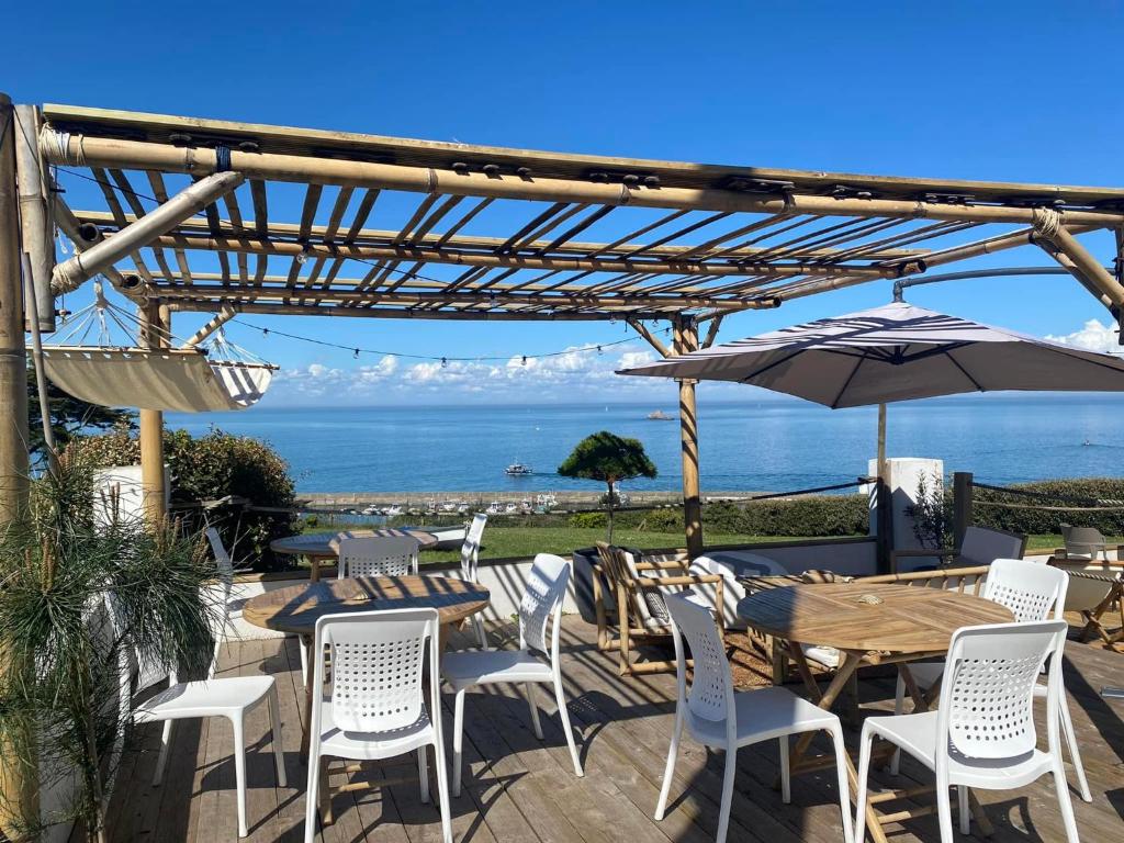 a patio with tables and chairs and an umbrella at Hôtel-Restaurant des Iles in Houat